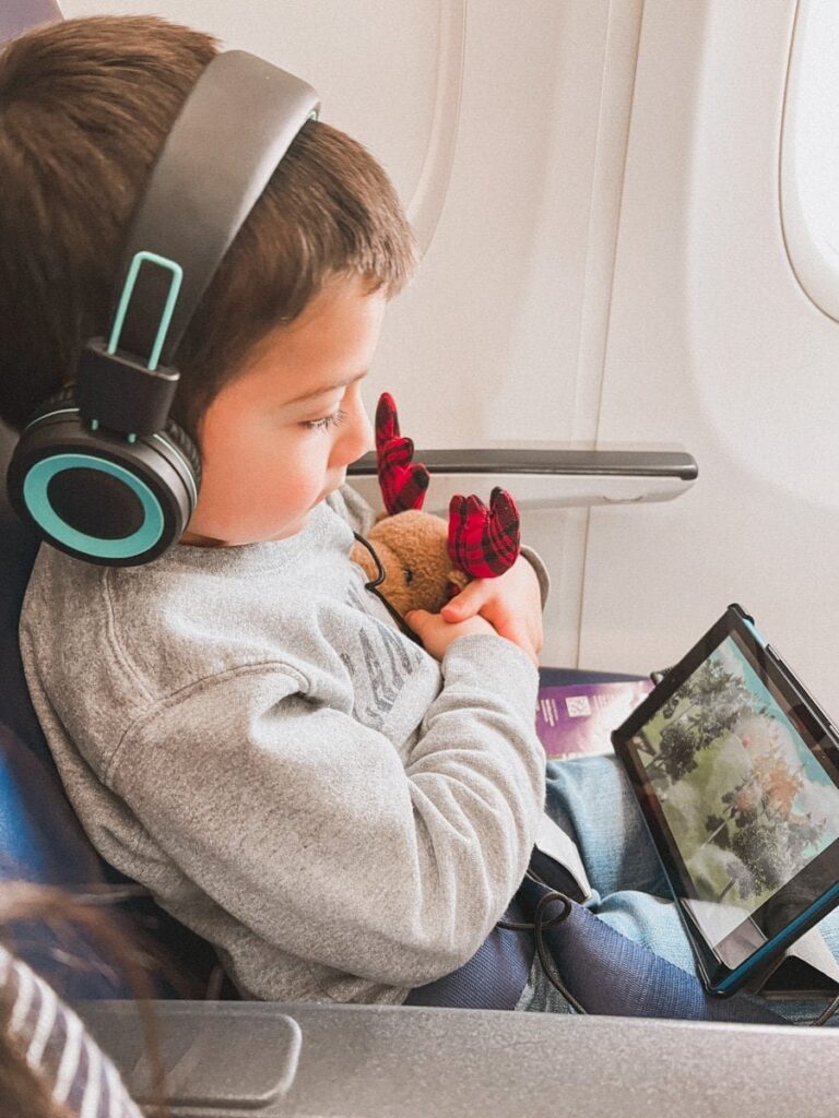 boy holding stuffed animal and watching tablet on flights with kids
